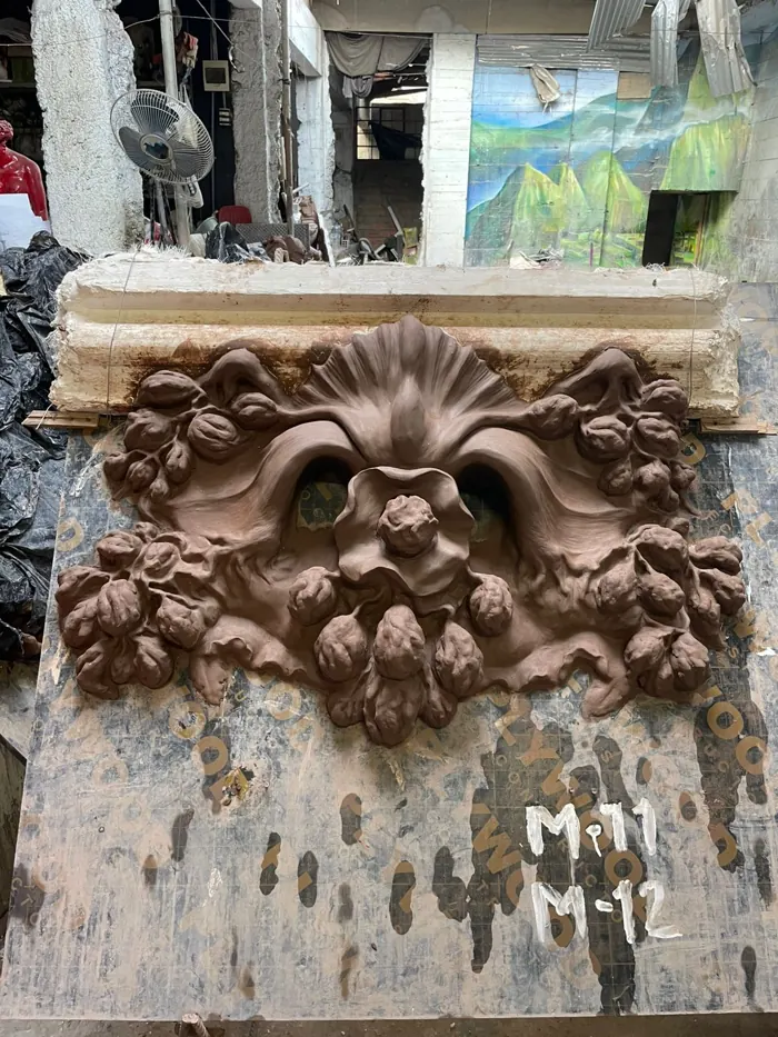 Mascarón con un rostro entre flores, modelado en arcilla